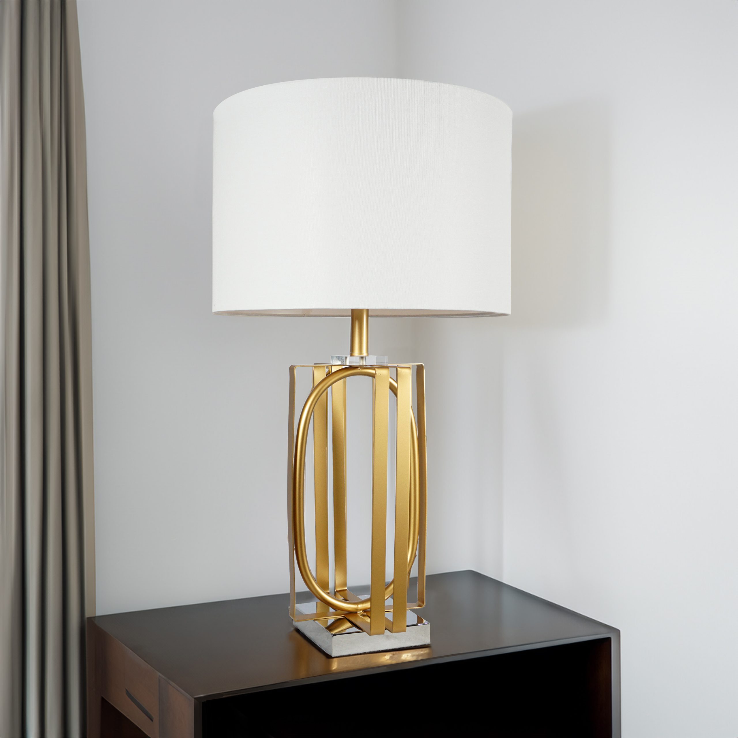The #6283T "Golden" Touch Lamp set of 2 features large white cylindrical shades and gold and silver geometric metal bases, displayed on a dark wooden surface against a white wall and grey curtain.